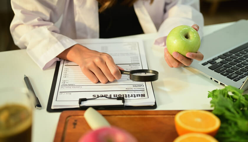 Food Inspection nutritionist is holding apple along with other fruits to inspect the quality of fruits.